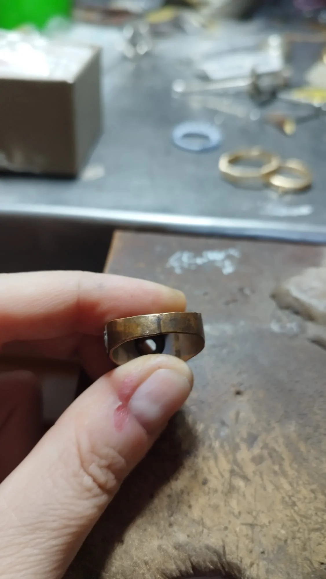 An old, worn gold band held between two fingers at the bench