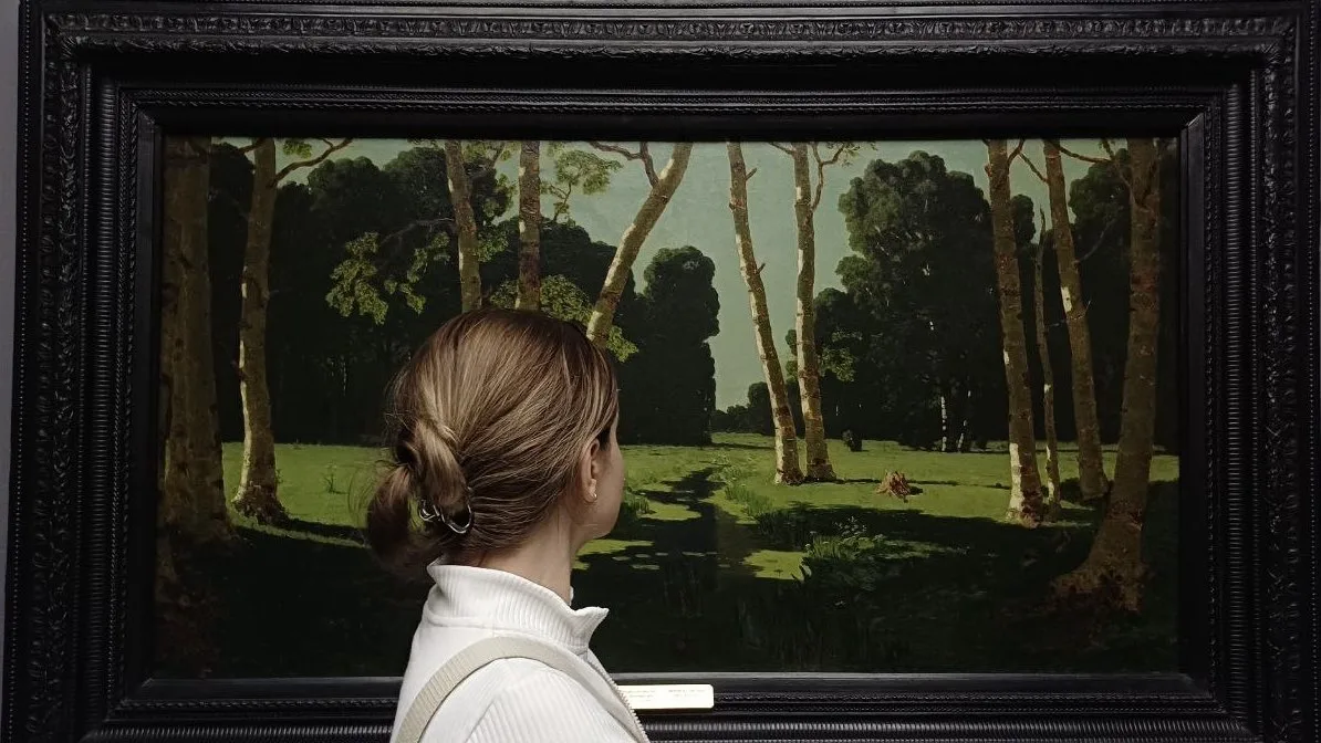Dasha looking at a painting of a birch grove