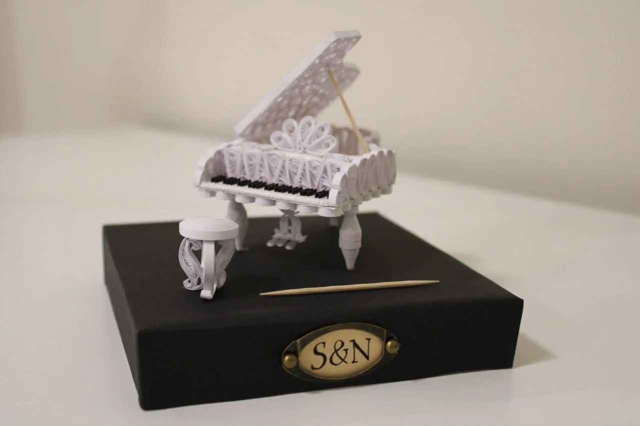 A grand piano built from rolled strips of paper, on a black base