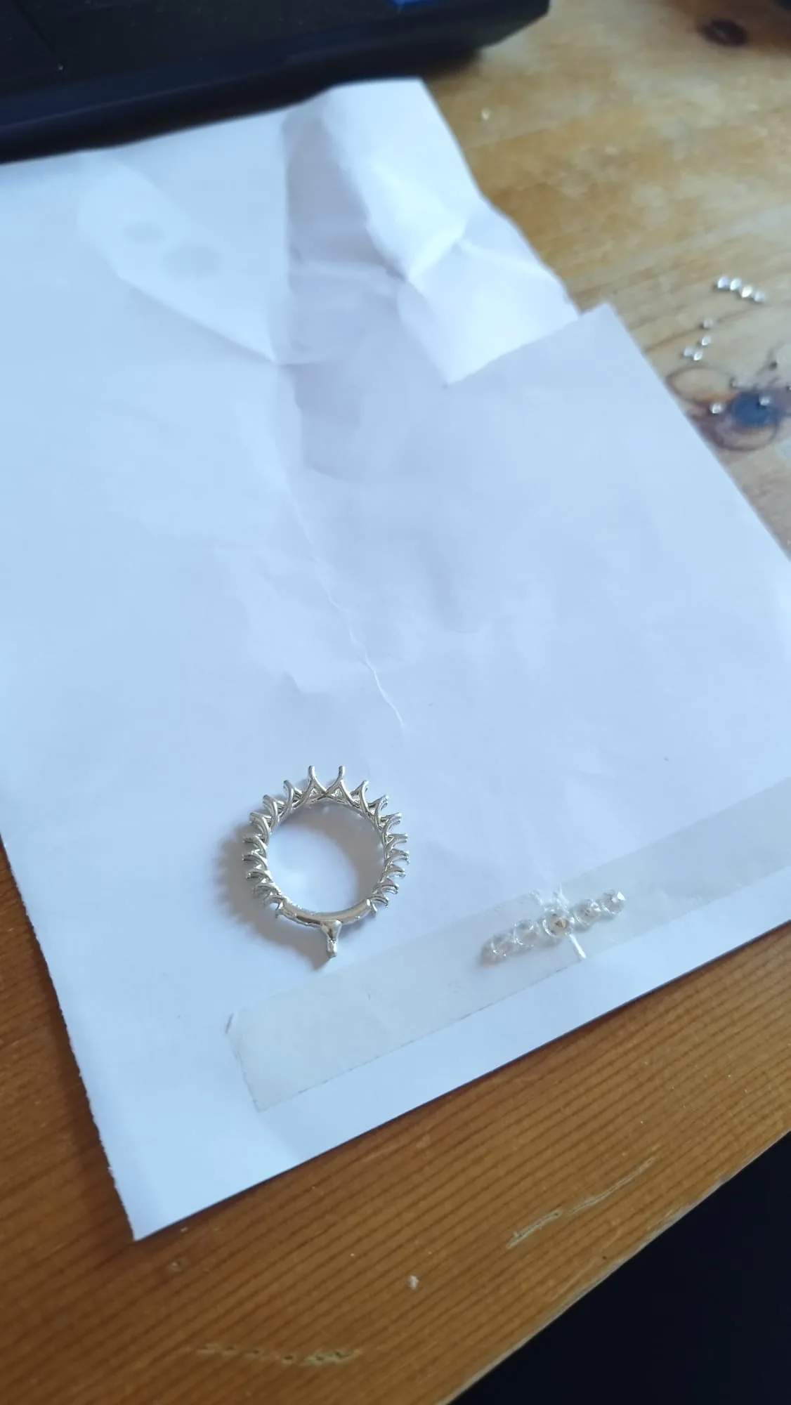 The cast ring on a sheet of paper, the diamonds lined up on tape beside it
